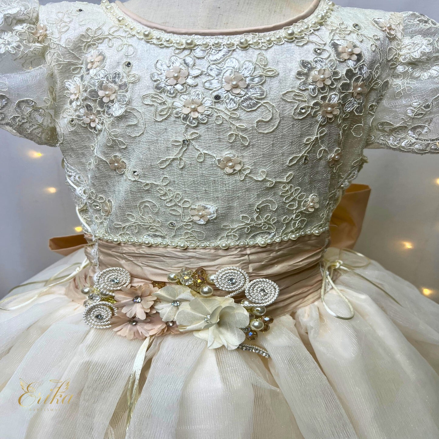 Close-up of pearl beadwork and 3D floral appliqués on a pearl-toned artisan communion gown
