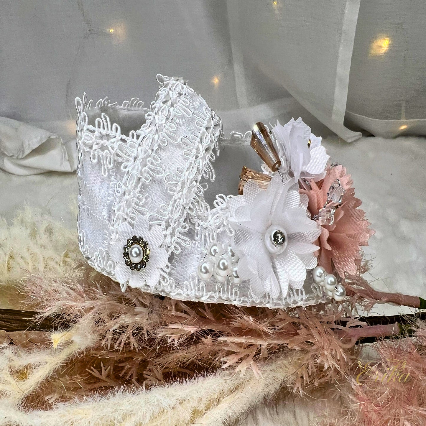 White lace christening shoes with pink flowers, crystal rhinestones, and brown ribbon accents.