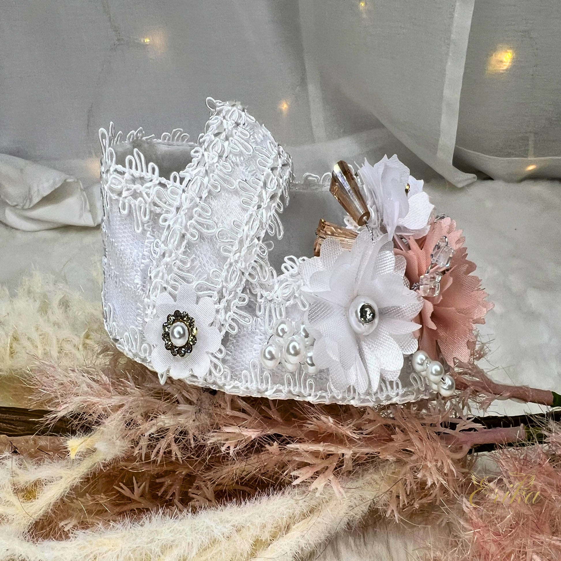 White lace christening shoes with pink flowers, crystal rhinestones, and brown ribbon accents.