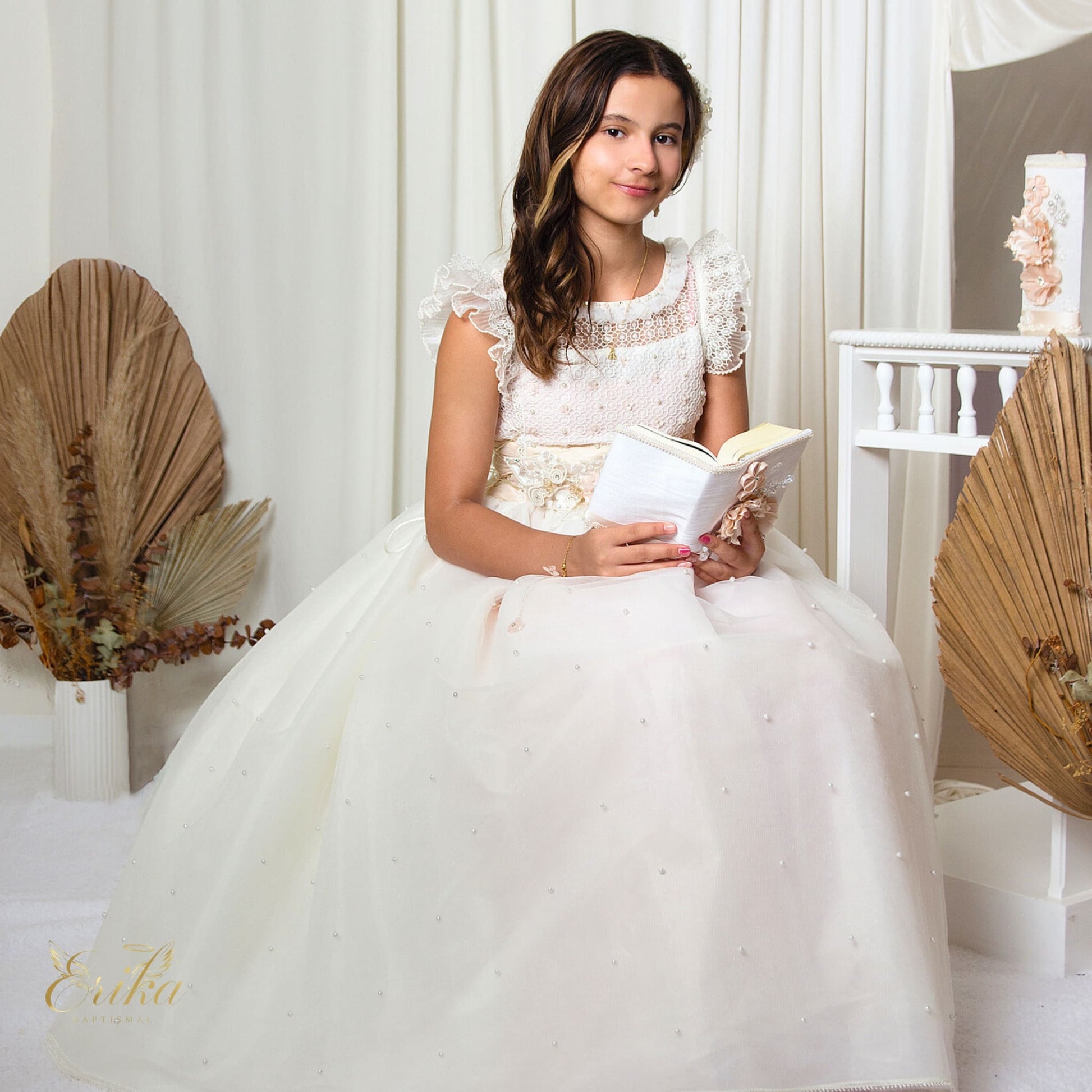 Young girl wearing a white First Communion dress with scattered pearls and lace sleeves
