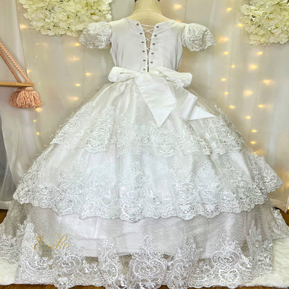 Back view of a white tiered Communion dress featuring a large satin bow and corset back