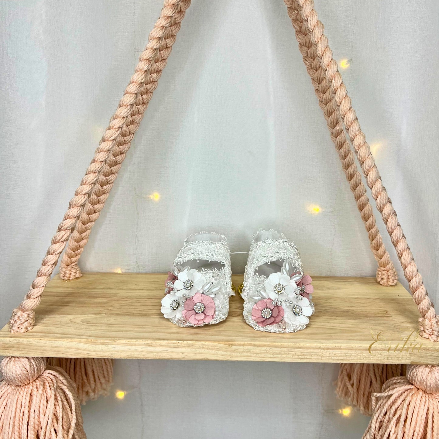 Ornate baby girl christening shoes decorated with pearls, crystals, and delicate pink blossoms