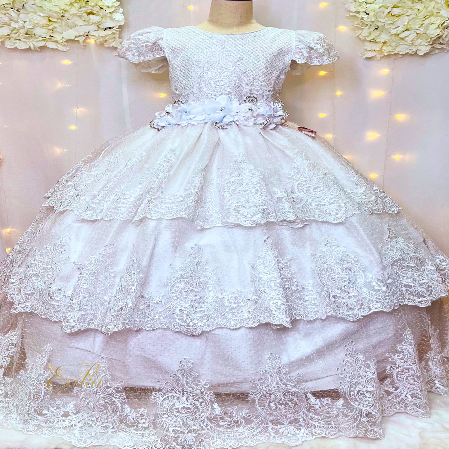 Detailed view of the tiered lace skirt layers on a luxury white Communion dress