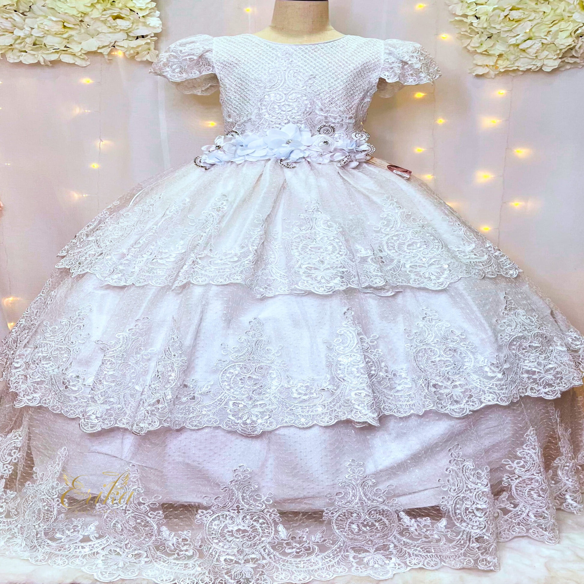 Detailed view of the tiered lace skirt layers on a luxury white Communion dress