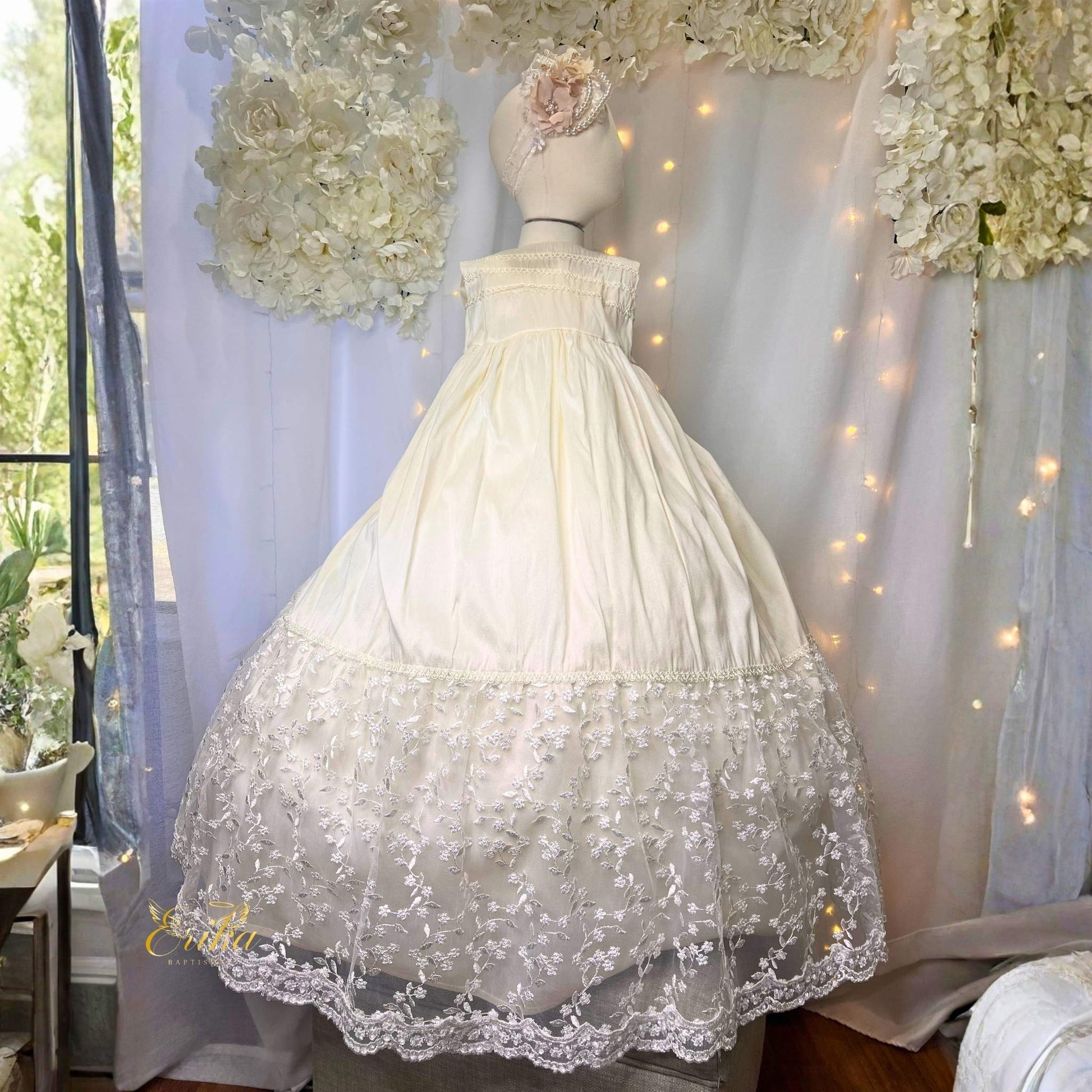 traditional long baby christening gown with lace ruffles and floral waistband in soft flowing fabric