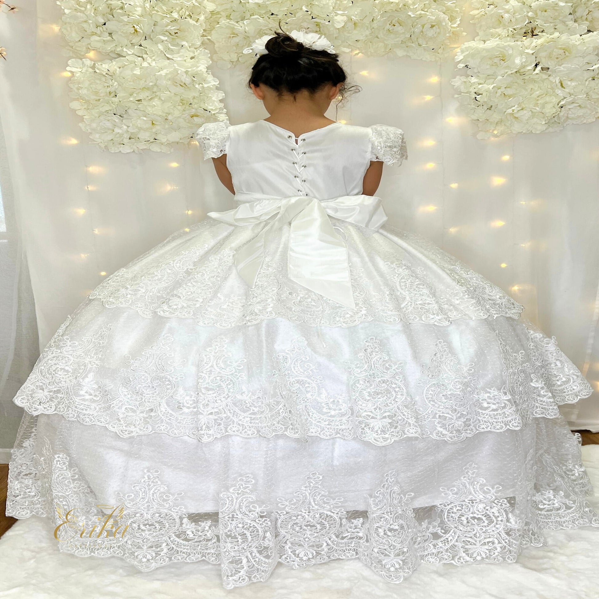 Close-up of the delicate lace bodice and floral belt on a white First Communion gown