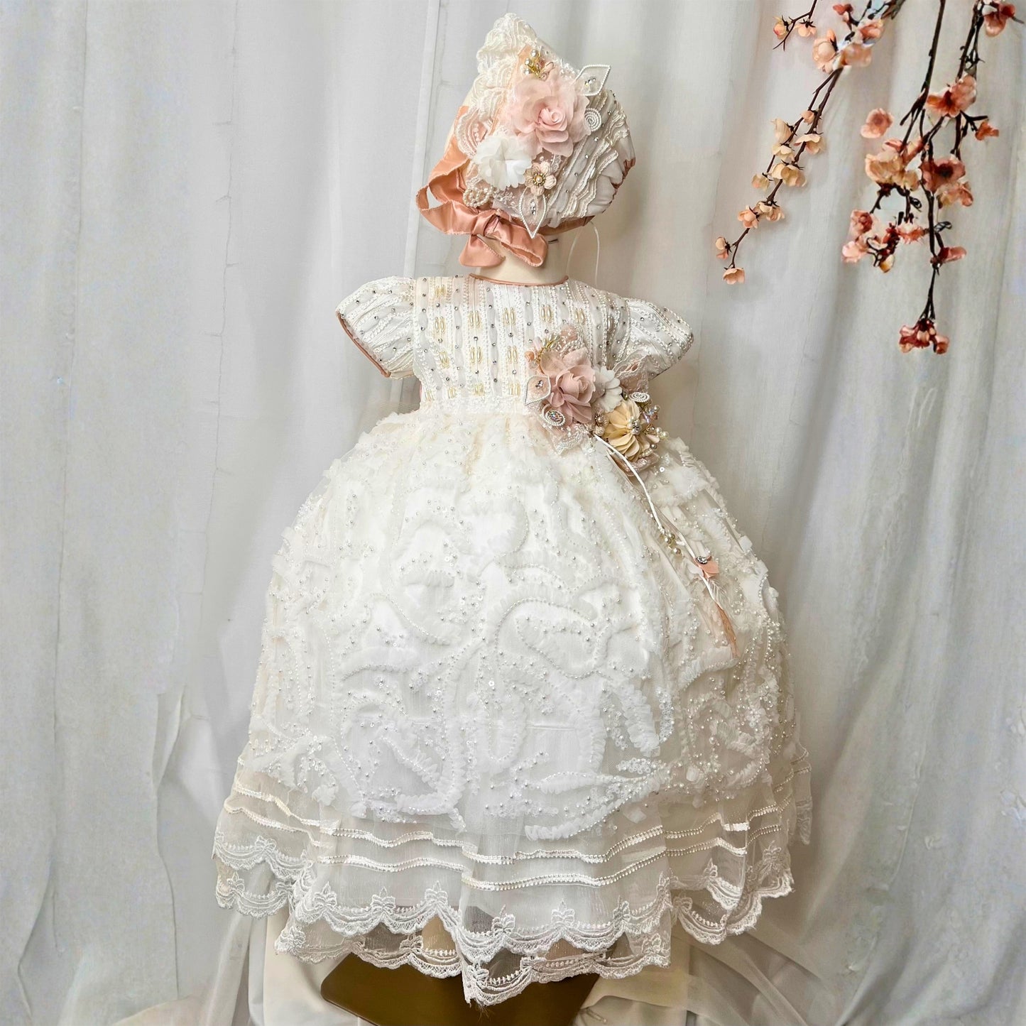white baby christening dress with soft ruffles and floral embroidered details in lightweight fabric