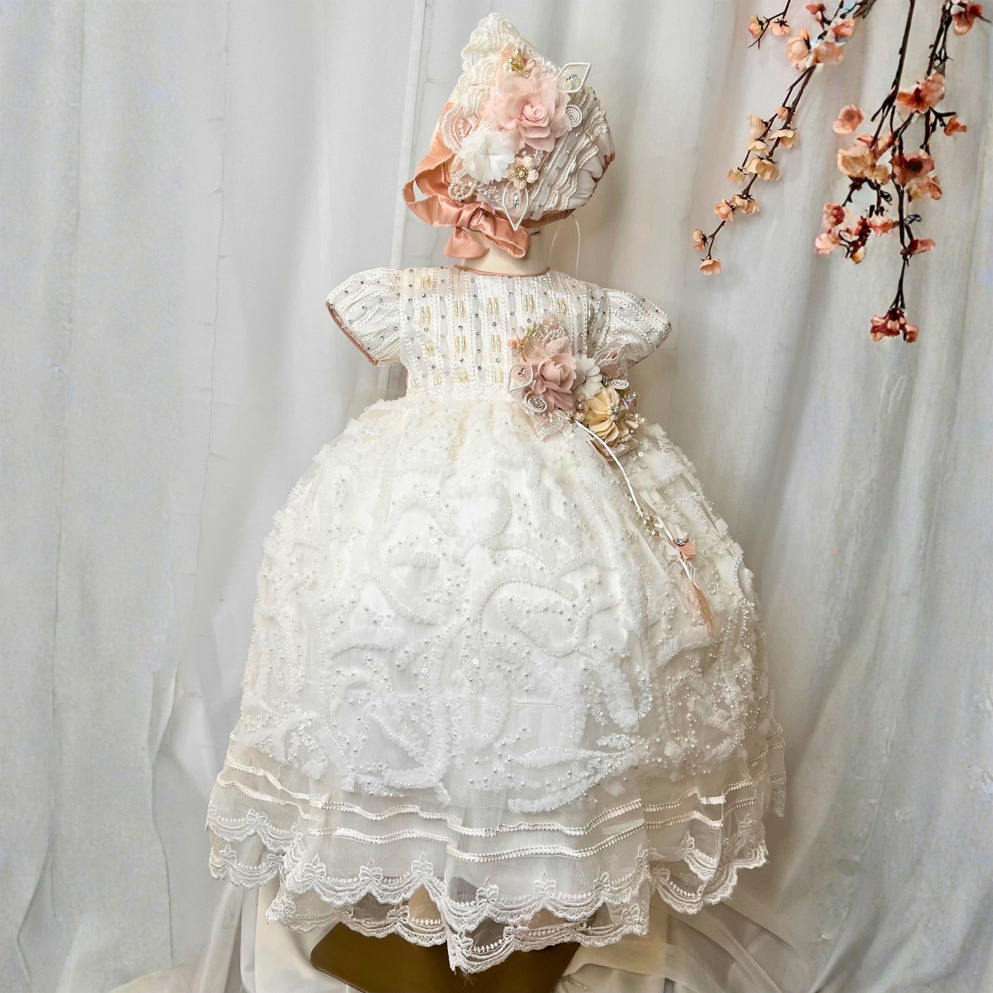 white baby christening dress with soft ruffles and floral embroidered details in lightweight fabric