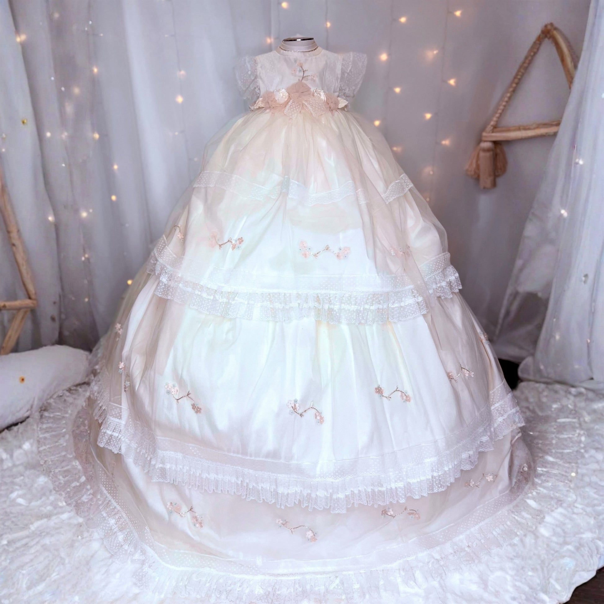 long white baby christening dress with small floral embroidery and soft tulle detail at the hem